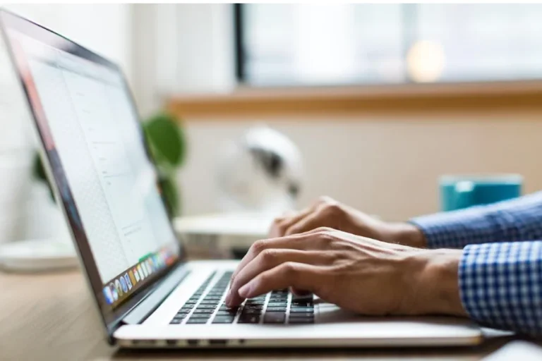 A person focused on typing on a laptop, symbolizing the rise of cloud faxing in small business operations.